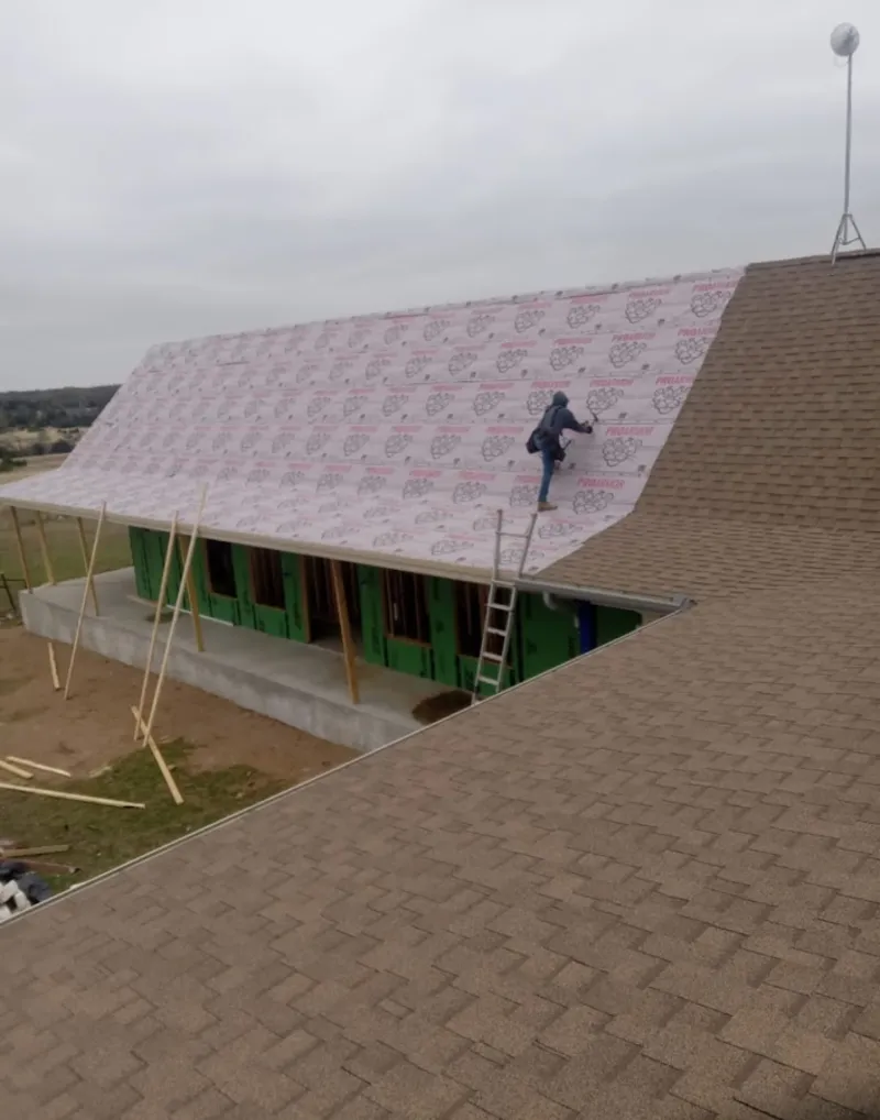 Worker preparing underlayment for a metal roof installation in On Top of the World